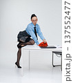 Young calm white woman in office attire working talking on vintage red phone, isolated on white background. In a blue shirt with a tie. Business occupation. 137552477