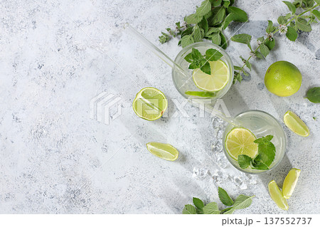 Summer drink with lemon, mint, lime and orange on a light table, mojito or cocktail improves metabolism and promotes weight loss, detox diet and healthy lifestyle concept, summer party advertisement. Summer drink with lemon, mint, lime and orange on a light table, mojito or cocktail improves metabolism and promotes weight loss, detox diet and healthy lifestyle concept, summer party advertisement. 137552737