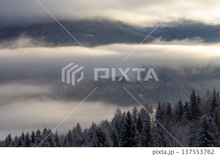 Sunrise makes a breakthrough in the mist between the mountains Sunrise makes a breakthrough in the mist between the mountains 137553762