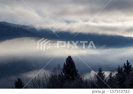 Sunrise makes a breakthrough in the mist between the mountains Sunrise makes a breakthrough in the mist between the mountains 137553783