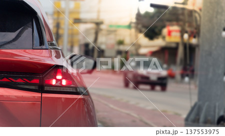 Close up taillight of luxury red car. Blurred light coming from the car from the brake lights. Background of traffic is light in small towns with few cars driving at Thailand. 137553975