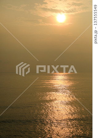 Sun sets over the ocean creating golden reflections on water 137555549