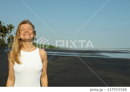 A woman smiles on a black sand beach in Bali 137555588
