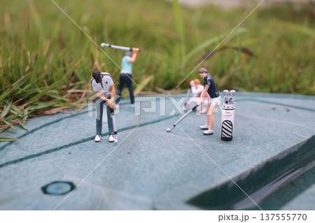 Tiny Golf Figurines Train Together On Textured Green Surface Tiny Golf Figurines Train Together On Textured Green Surface 137555770