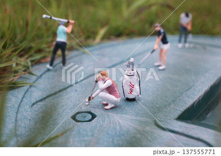 Tiny Golf Figurines Train Together On Textured Green Surface 137555771