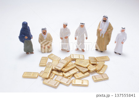 Miniature desert figures surrounding pile of gold bars Miniature desert figures surrounding pile of gold bars 137555841