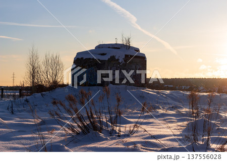Graffiti-covered old brick bunker sits atop a snowy hill at sunset, winter landscape with dry grass in foreground Graffiti-covered old brick bunker sits atop a snowy hill at sunset, winter landscape with dry grass in foreground 137556028