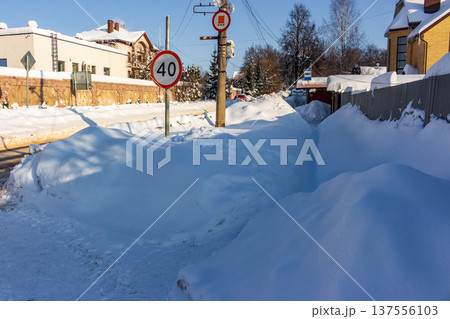 Deep snowdrifts line a roadside path near a 40 speed limit sign under a clear winter sky Deep snowdrifts line a roadside path near a 40 speed limit sign under a clear winter sky 137556103