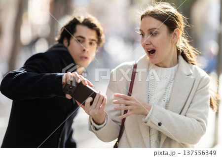 Male thief trying to snatch mobile phone of frightened woman on city 137556349