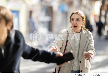 Young man snatches phone from woman on street Young man snatches phone from woman on street 137556360
