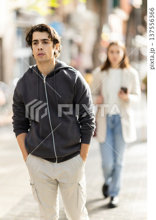 Upset young man walking away from woman on street Upset young man walking away from woman on street 137556366
