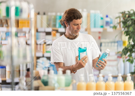 Adult man chooses mouthwash at pharmacy 137556367