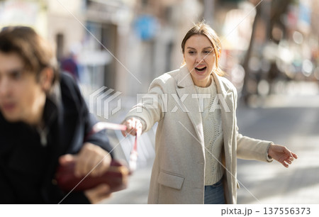 Young man snatching handbag from woman on street 137556373