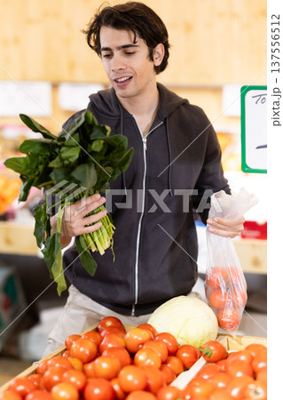 Guy shopping, examine vegetable in store and buy elect spinach Guy shopping, examine vegetable in store and buy elect spinach 137556512