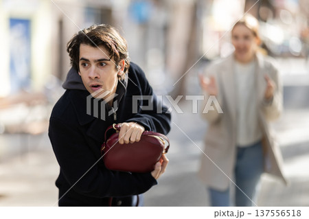 Young man snatching handbag from woman on street 137556518