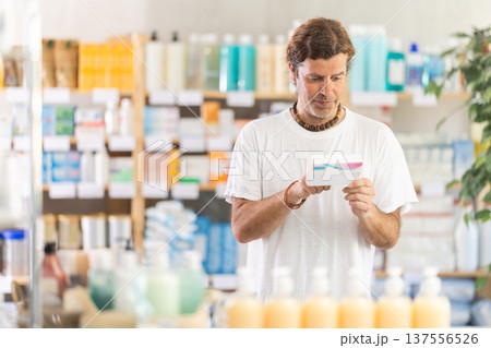 adult man chooses a package of pills in a pharmacy 137556526
