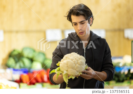 Male shopper selects cauliflower at grocery store Male shopper selects cauliflower at grocery store 137556531