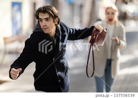 Male thief stealing woman bag on street Male thief stealing woman bag on street 137556539