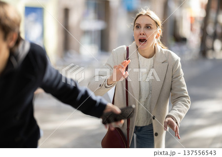 Young man snatches phone from woman on street Young man snatches phone from woman on street 137556543