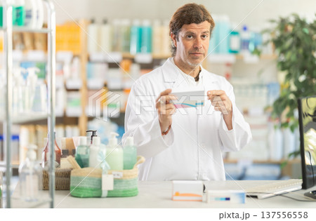 Adult male pharmacist working at computer and offering pills 137556558