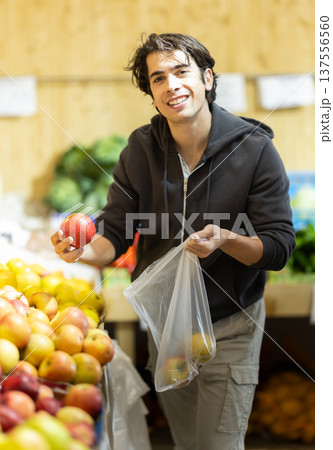Young man choosing apples in vegetable shop 137556560