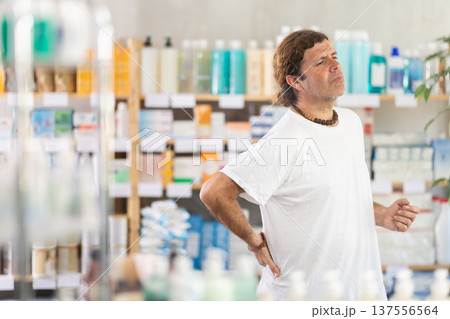 man holding his back in a pharmacy 137556564