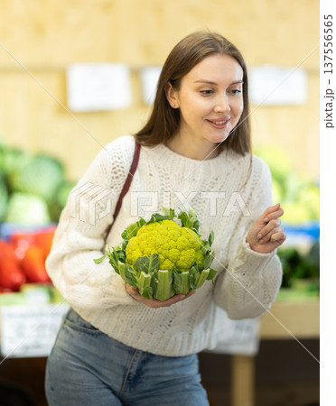 Female shopper selects cauliflower at grocery store 137556565