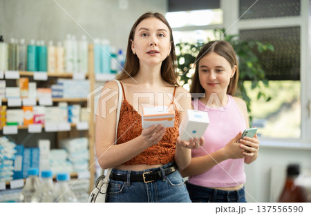 Woman with teen girl are busy choosing tablet pills at pharmacy 137556590