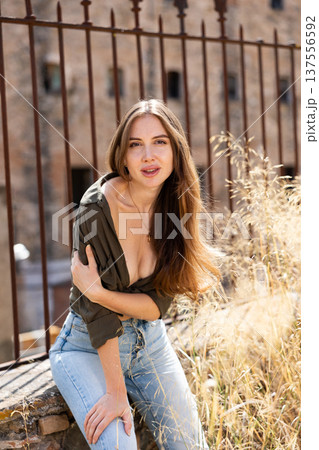 Portrait of sexy blonde woman with puffy hair in shirt and jeans on summer street 137556592