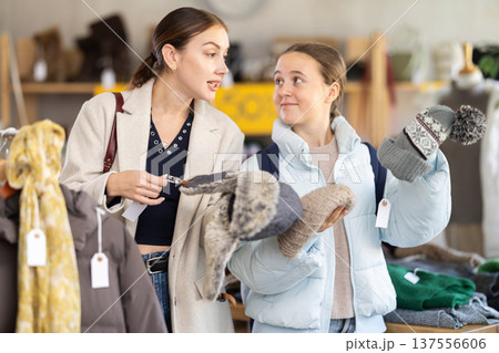 Teen girl with mother choosing hat in clothing store Teen girl with mother choosing hat in clothing store 137556606