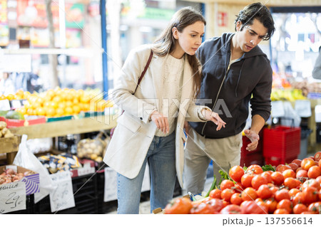 Married couple chooses ripe tomatoes at grocery supermarket. 137556614