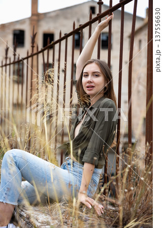 Charming young svelte woman leaning against fence 137556630