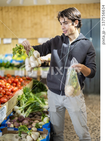 Young man chooses turnip at vegetable shop 137556634