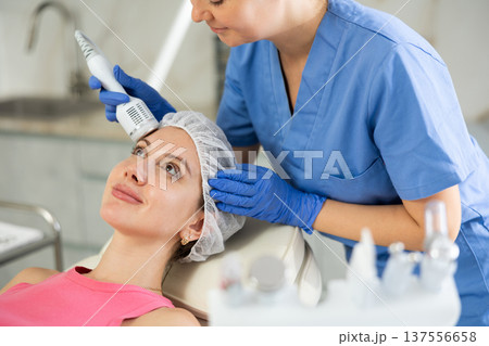 Caucasian brunette girl lying in spa while having facial treatment procedures with modern technologies shrink pores and repair damaged skin. Hardware cosmetology and dermatology 137556658