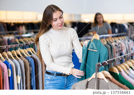Girl is deciding on turtleneck sweater in women cloths shop Girl is deciding on turtleneck sweater in women cloths shop 137556661