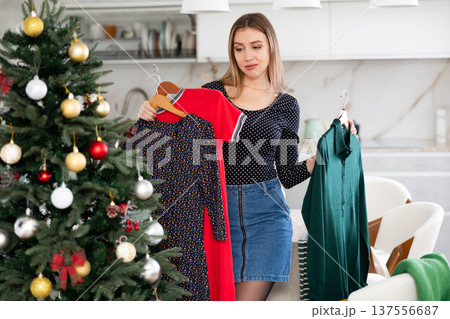 Upset woman not happy with her old dresses in wardrobe for Christmas celebration in apartment 137556687