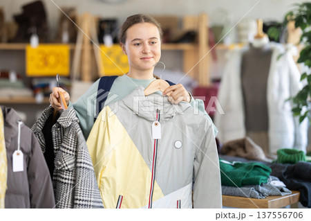 Teenage girl choosing something for autumn-winter in clothing store 137556706