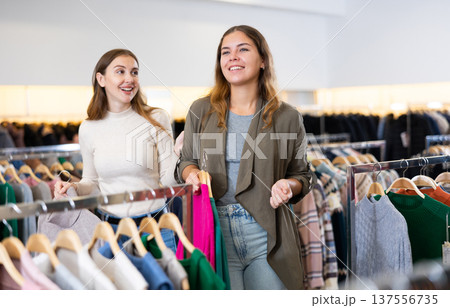 Two happy female friends are shopping in clothing store. Shopping young ladies Two happy female friends are shopping in clothing store. Shopping young ladies 137556735