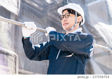 大規模修繕工事の現場で働く眼鏡の足場とび職人 137556754