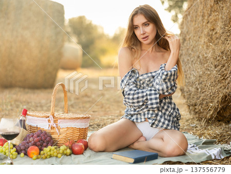 Young woman in shirt kneeling during picnic Young woman in shirt kneeling during picnic 137556779