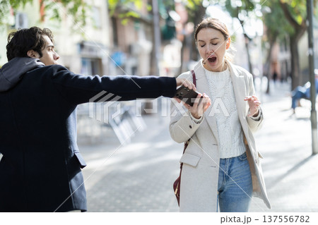 Young man snatches phone from woman on street Young man snatches phone from woman on street 137556782