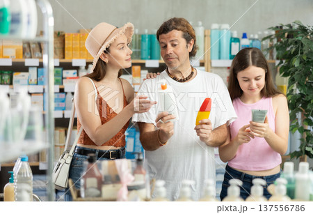 Father, mother and daughter choose sunscreen together at drugstore 137556786