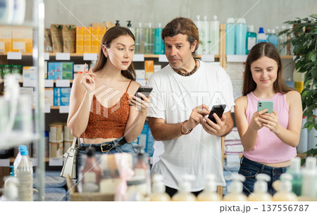 Father, daughter and mother read prescription on mobile phone screen and look for medicine in modern pharmacy Father, daughter and mother read prescription on mobile phone screen and look for medicine in modern pharmacy 137556787
