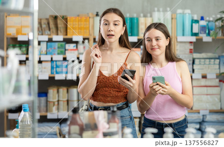 Woman and adolescence girl in pharmacy with phone Woman and adolescence girl in pharmacy with phone 137556827