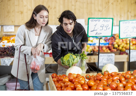 Young couple choose tomatoes and broccoli in store Young couple choose tomatoes and broccoli in store 137556837