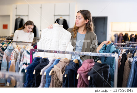 Young woman choosing insulated vest in store Young woman choosing insulated vest in store 137556848