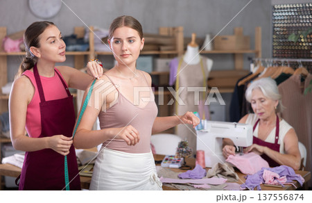 adult female dressmaker takes measurements for a client in the workshop adult female dressmaker takes measurements for a client in the workshop 137556874