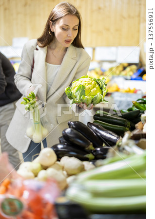 Young woman chooses broccoli at vegetable shop Young woman chooses broccoli at vegetable shop 137556911