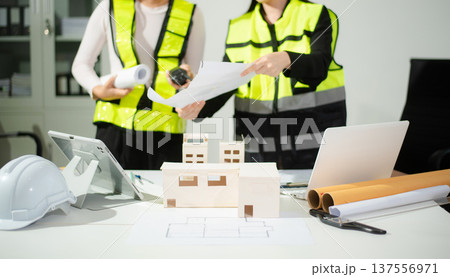 Engineer teams meeting working together wear worker helmets hardhat on construction site in modern city. Engineer teams meeting working together wear worker helmets hardhat on construction site in modern city. 137556971