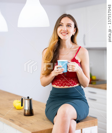Smiling woman drinking coffee at home Smiling woman drinking coffee at home 137557048
